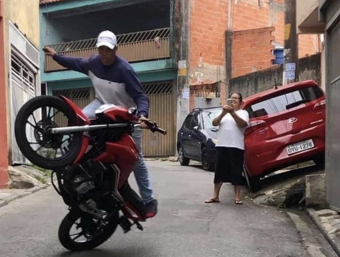 Homem dando grau na moto enquanto sua mãe filma, feliz da vida.